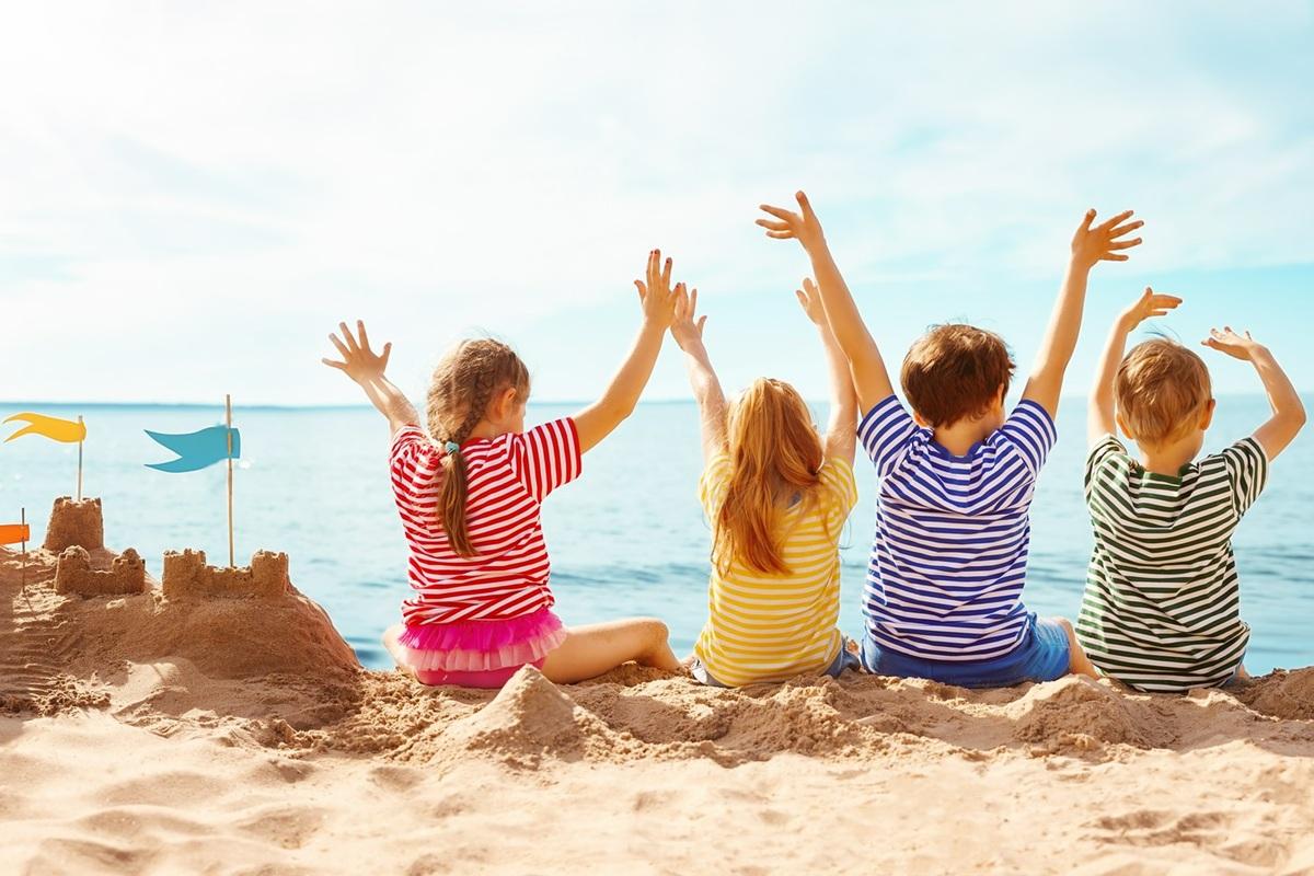 dzieci siedzące obok zamku z piasku
